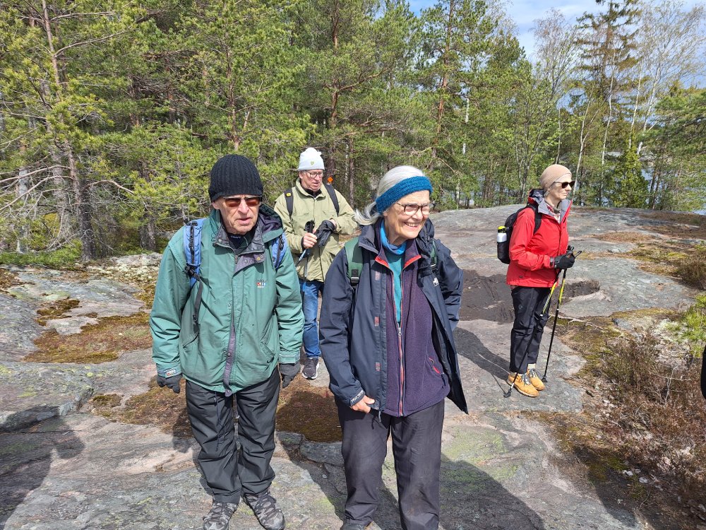 Människor på utfärd står i soligt väder på klippor.