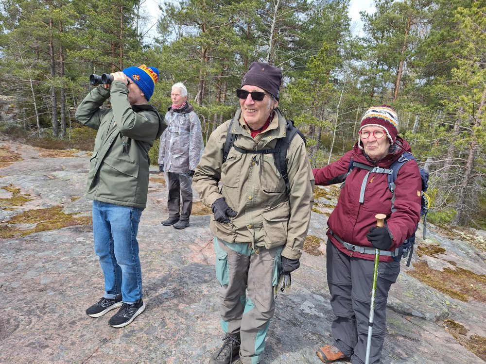 Människor står på klippor och ser på utsikten, en med kikare.