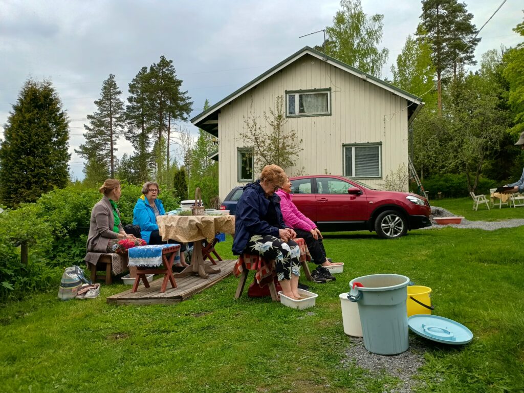 Naisia yrttijalkakylvyssä pilvisessä säässä puutarhassa