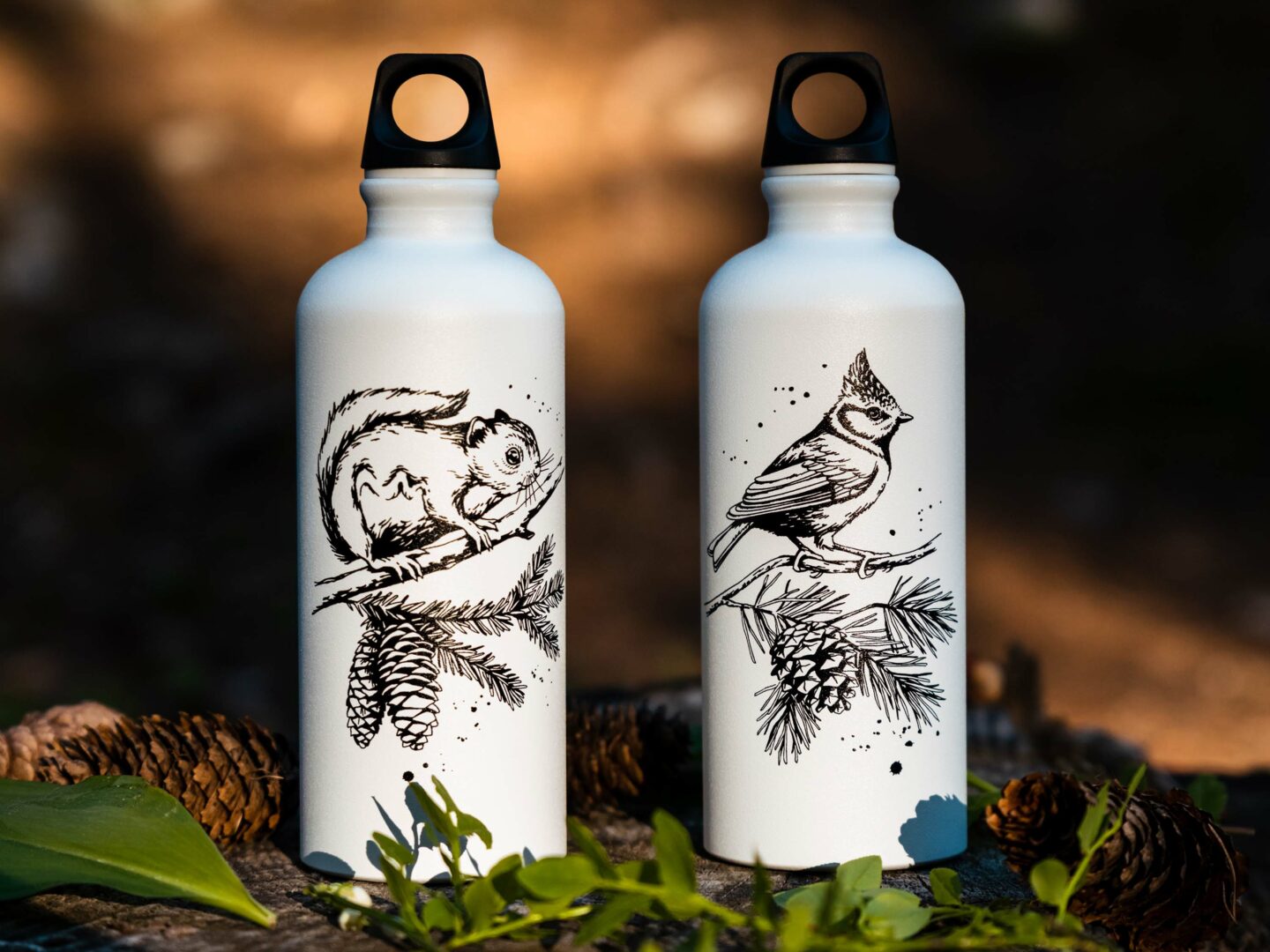 Metsätaustassa kuvattuna Uhanalaiset-juomapullosarjan pullot. Pulloissa valkealla pohjalla liito-oravan ja töyhtötiaisen piirroskuvat.