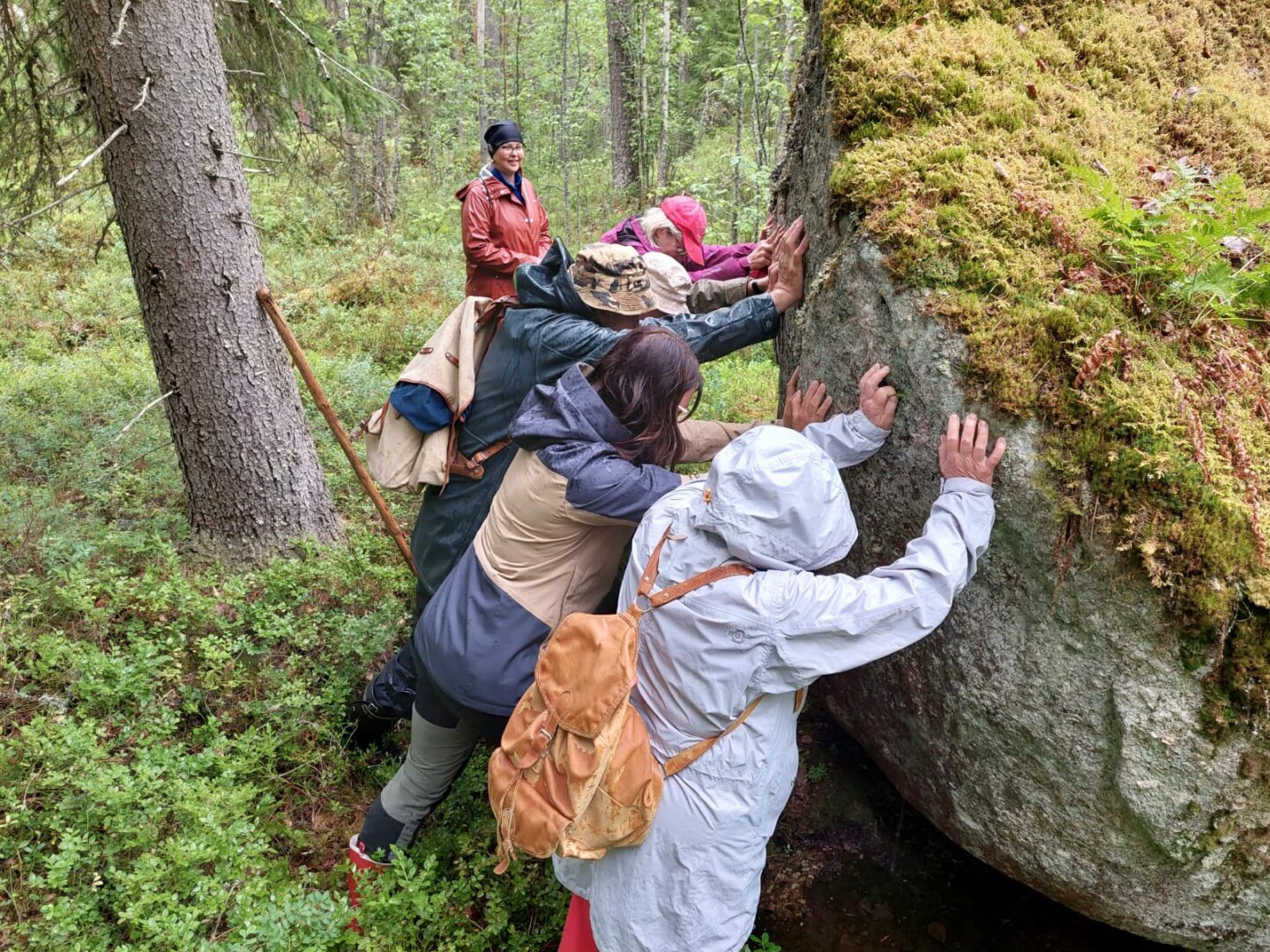 Retken osallistujat työntävät yhdessä Metsäkulman Leijuvaa kiveä.
