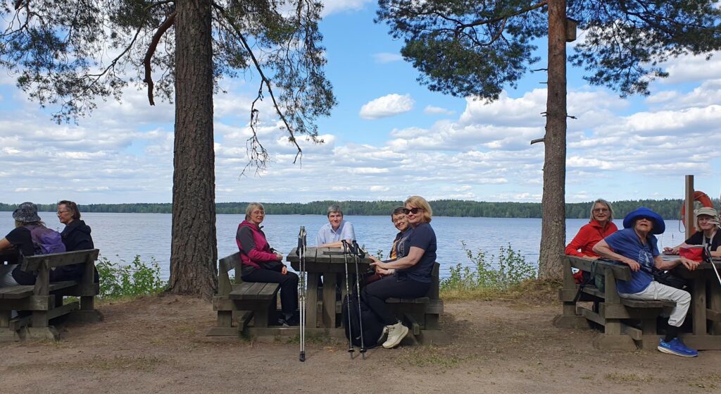 Eväotä nautitaan pirtinpöytien ääressä. Taustalla näkyy Kuivajärvi.