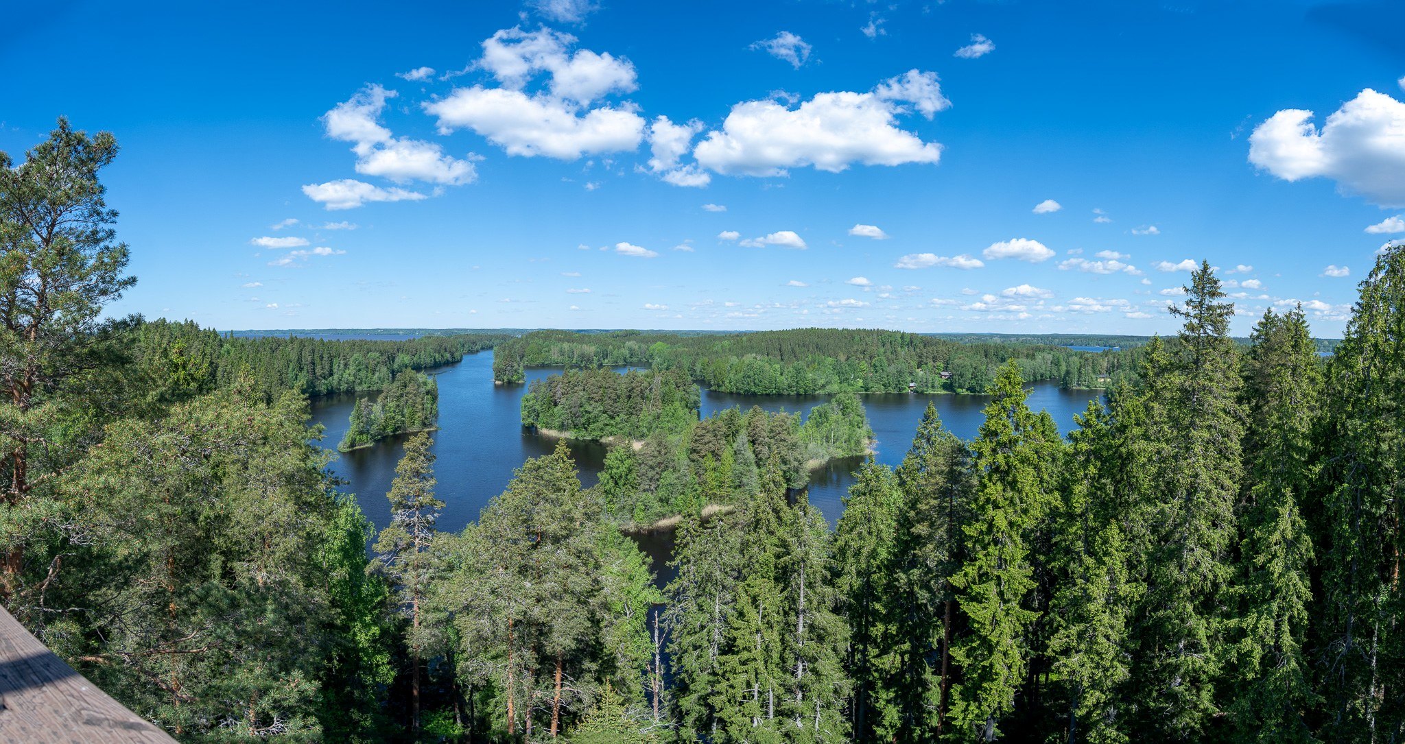 Maisema Kaukolanharjun näkötornista. Järviä, saaria. Aurinkoinen sää, lähes sininen taivas: muutama pikkuinen poutapilvi.