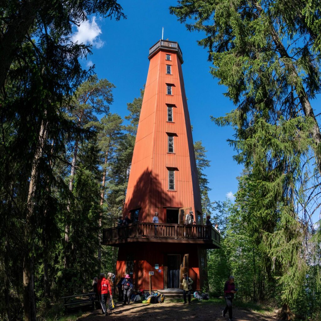Kaukolanharjun näkötorni on vanha, korkea, oranssinpunainen rakennus harjun päällä. Ympärillä kasvaa puita, kuten mäntyjä.