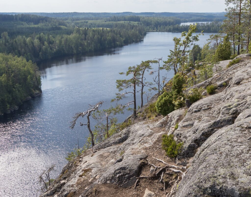 Maisema kallioisen jyrkänteen päältä, alla metsiä ja järviä.