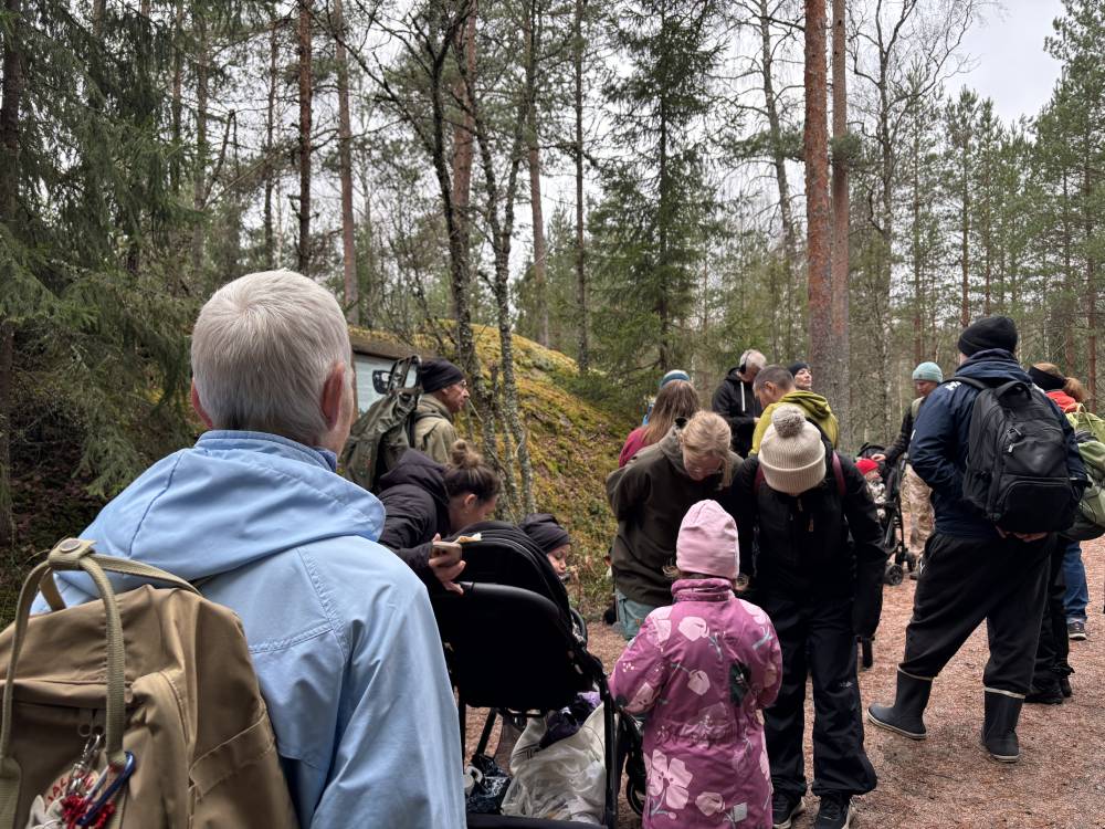 Människor i skogen. Närmast kameran en människa i blå jacka.