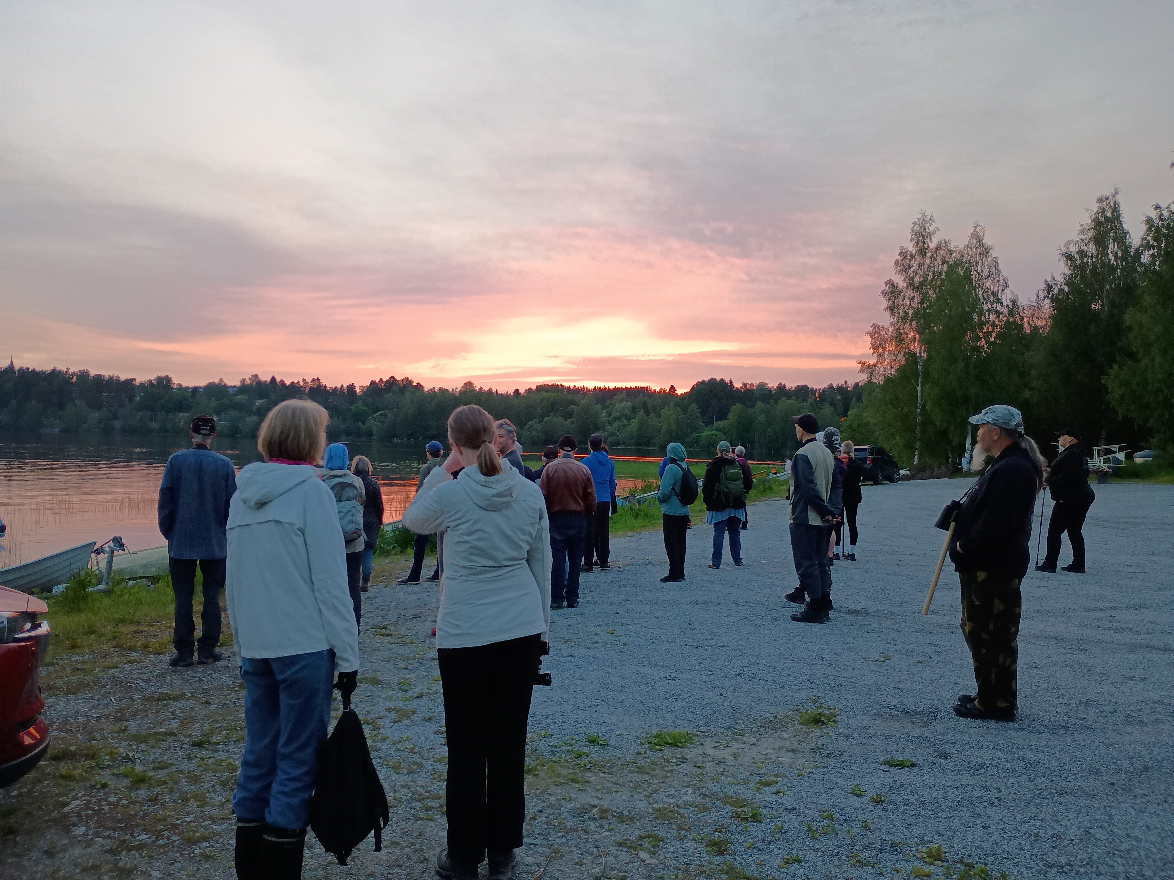 Ihmisiä rannalla auringonlaskun aikaan