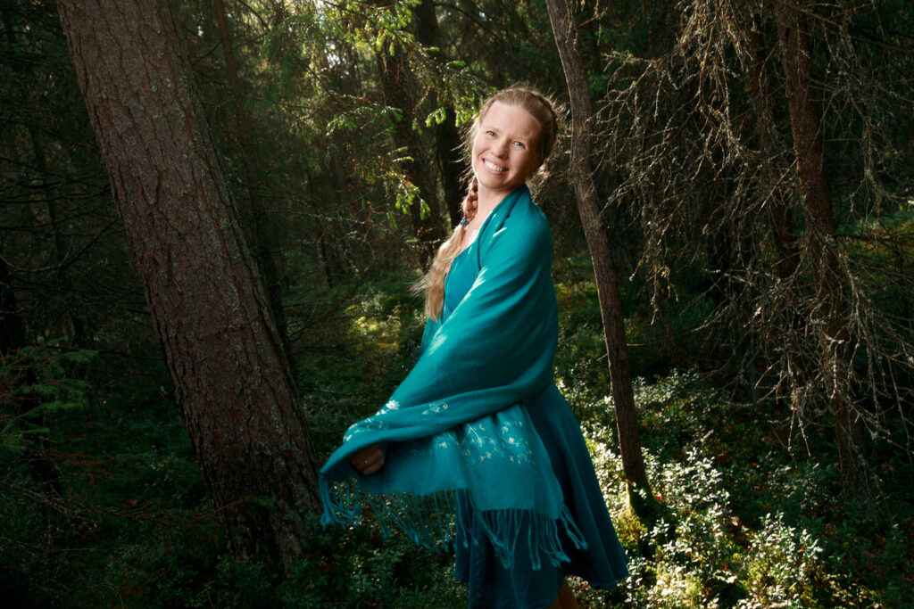 kuva hymyilevästä kirjailija Päivi Tuulikki Koskelasta metsän keskellä