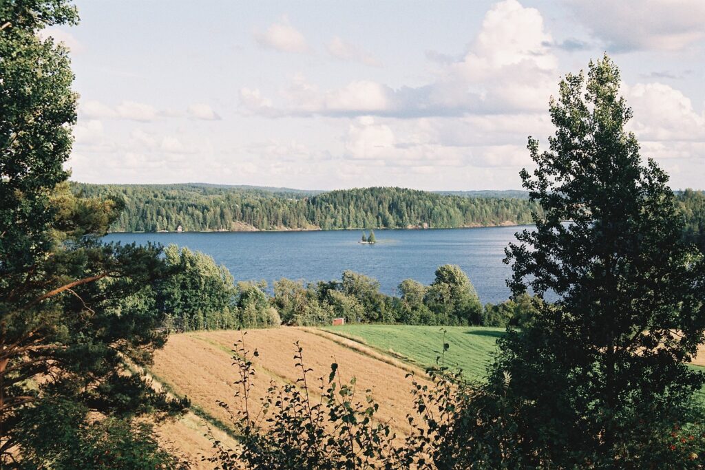 Kuvassa peltomaisema, jonka takana järvi.
