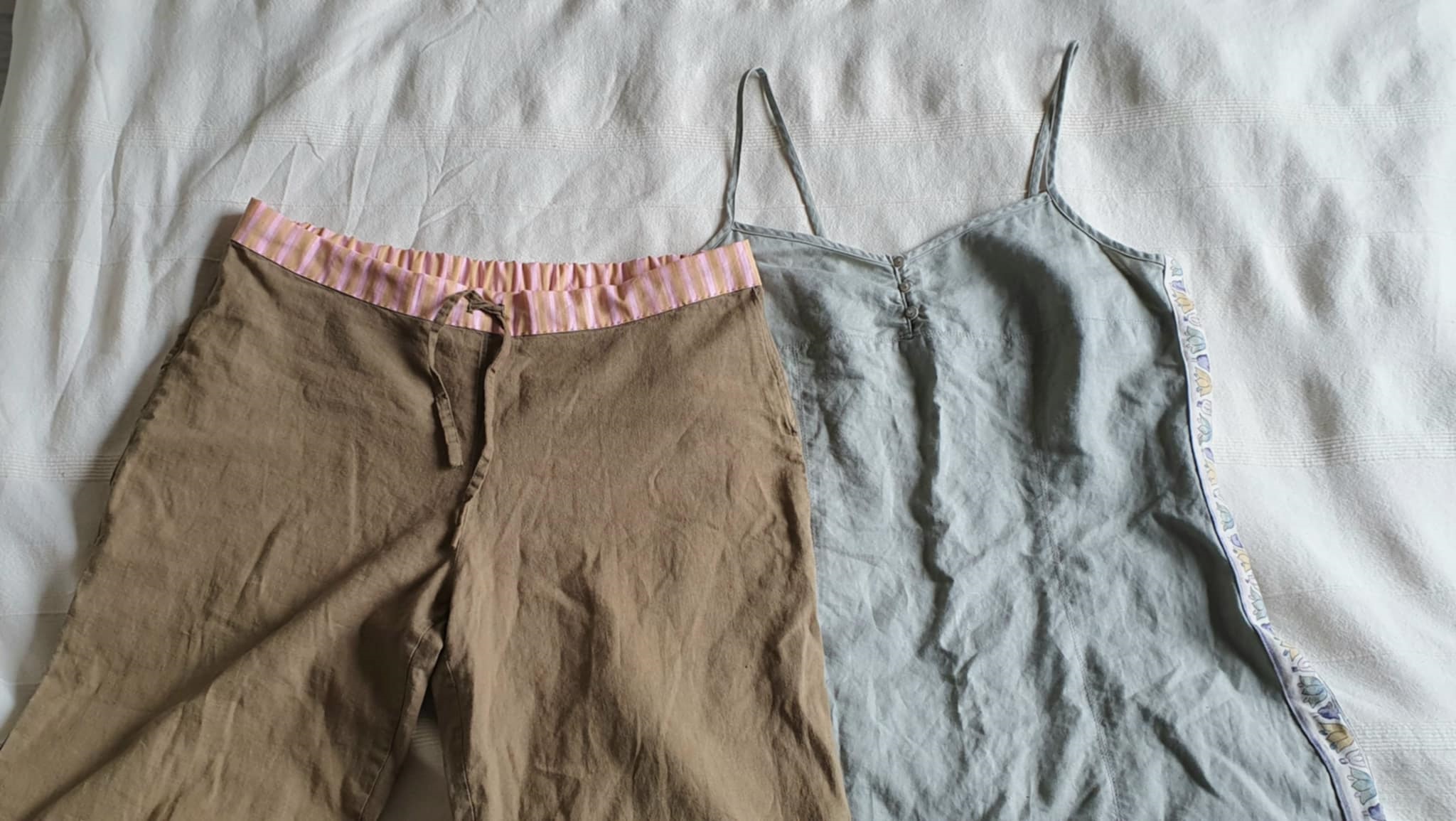 Pellavaiset housut, joihin on tehty uusi vy&ouml;t&auml;r&ouml; raitakankaasta ja pellavainen mekko, johon on tehty sivusaumoihin koristeellisesta kankaasta levennys