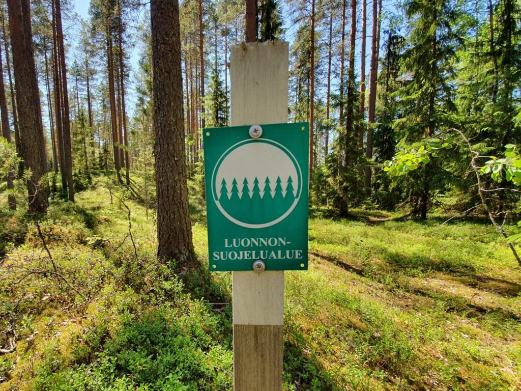 Kuvassa näkyy vihreä pylvääseen kiinnitetty merkki, jossa lukee