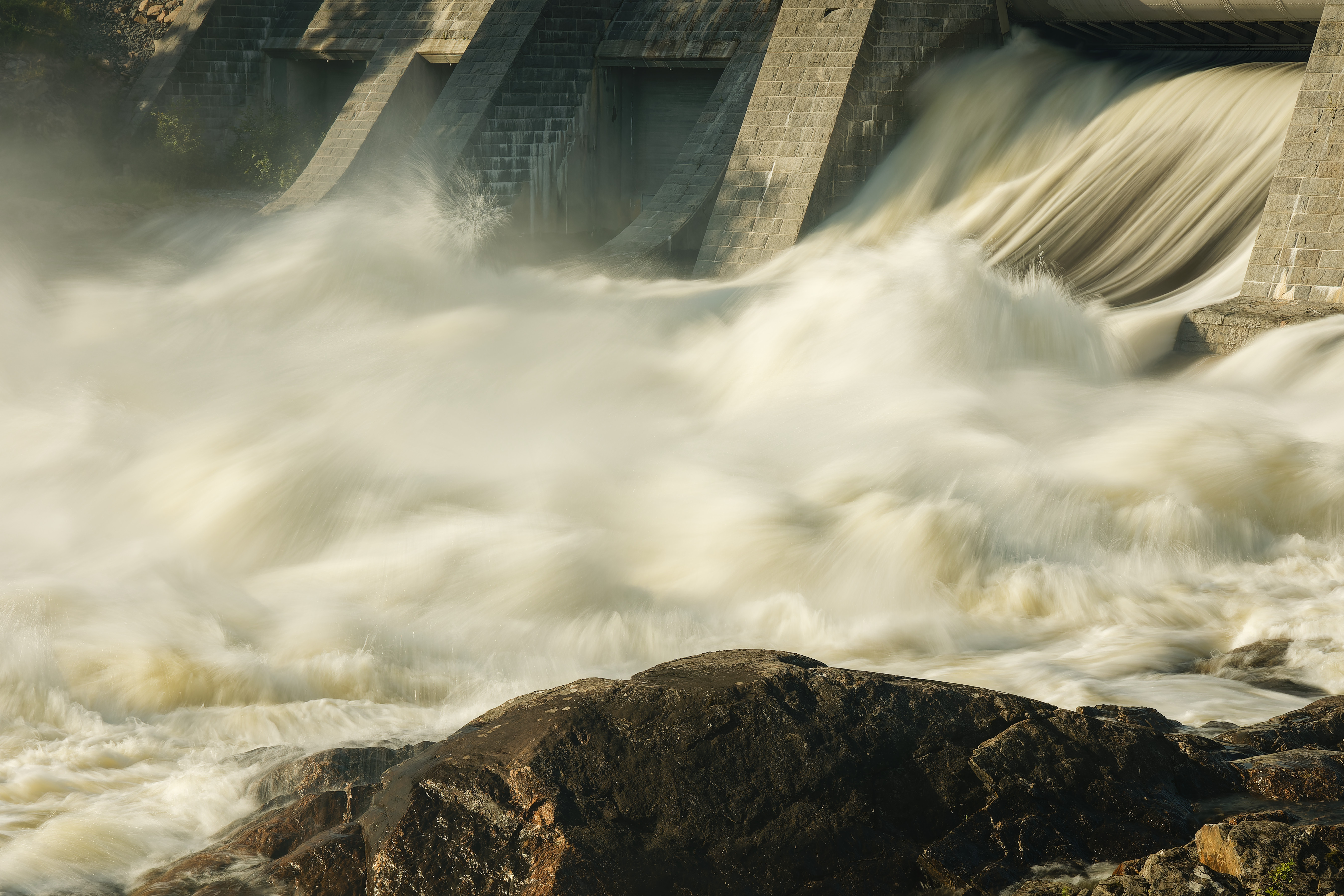 Vesivoimala, jossa vesi pauhuaa padon alapuolella.