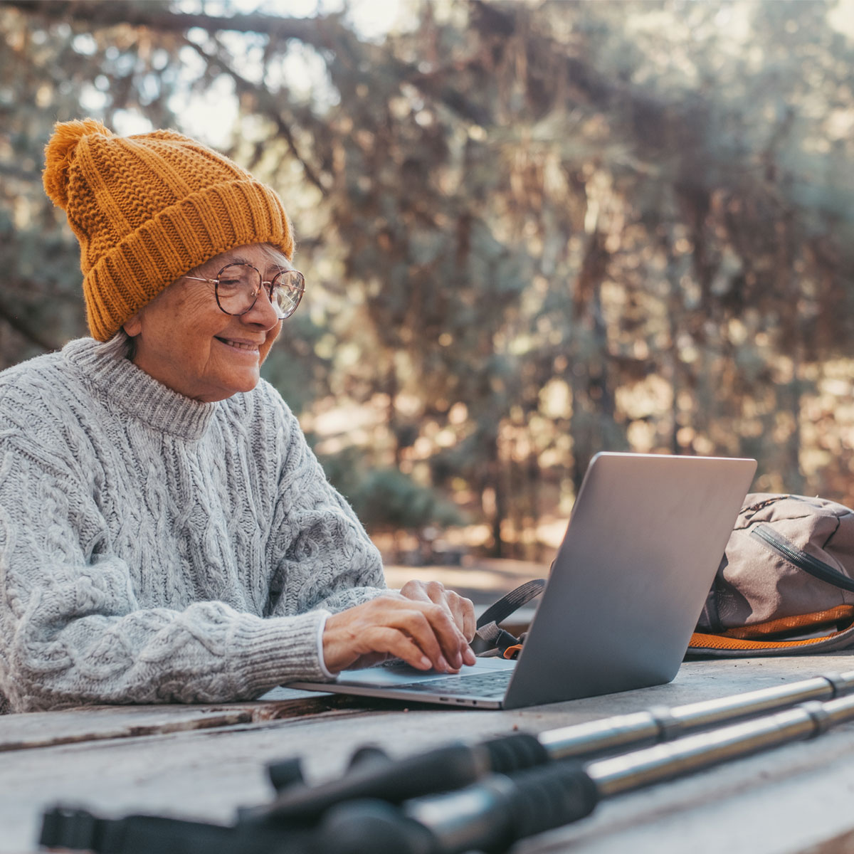 Retkeilijä istuu taukopaikalla tietokoneen äärellä ja luonnon ympäröimänä.