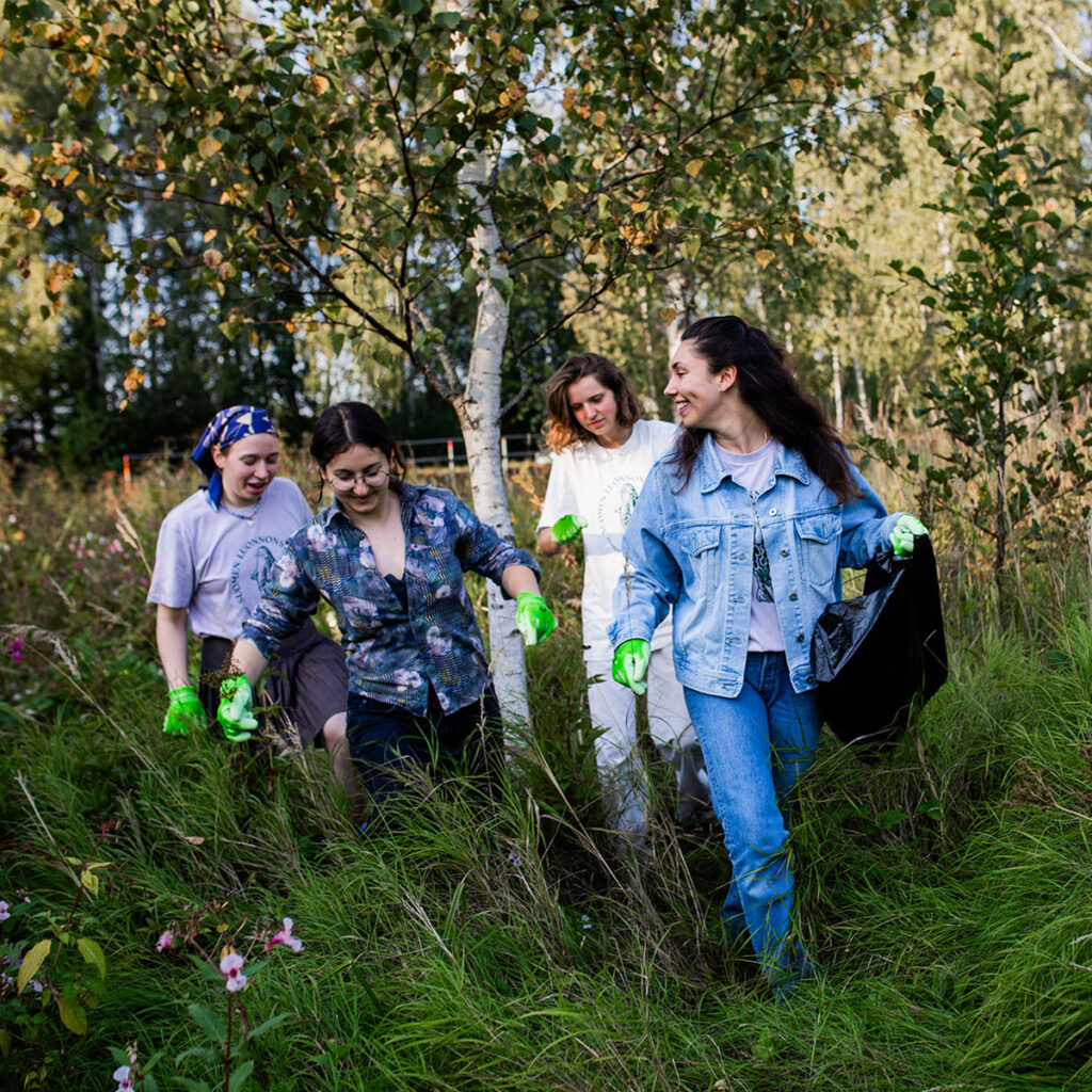 Neljä iloista talkoolaista luonnossa.