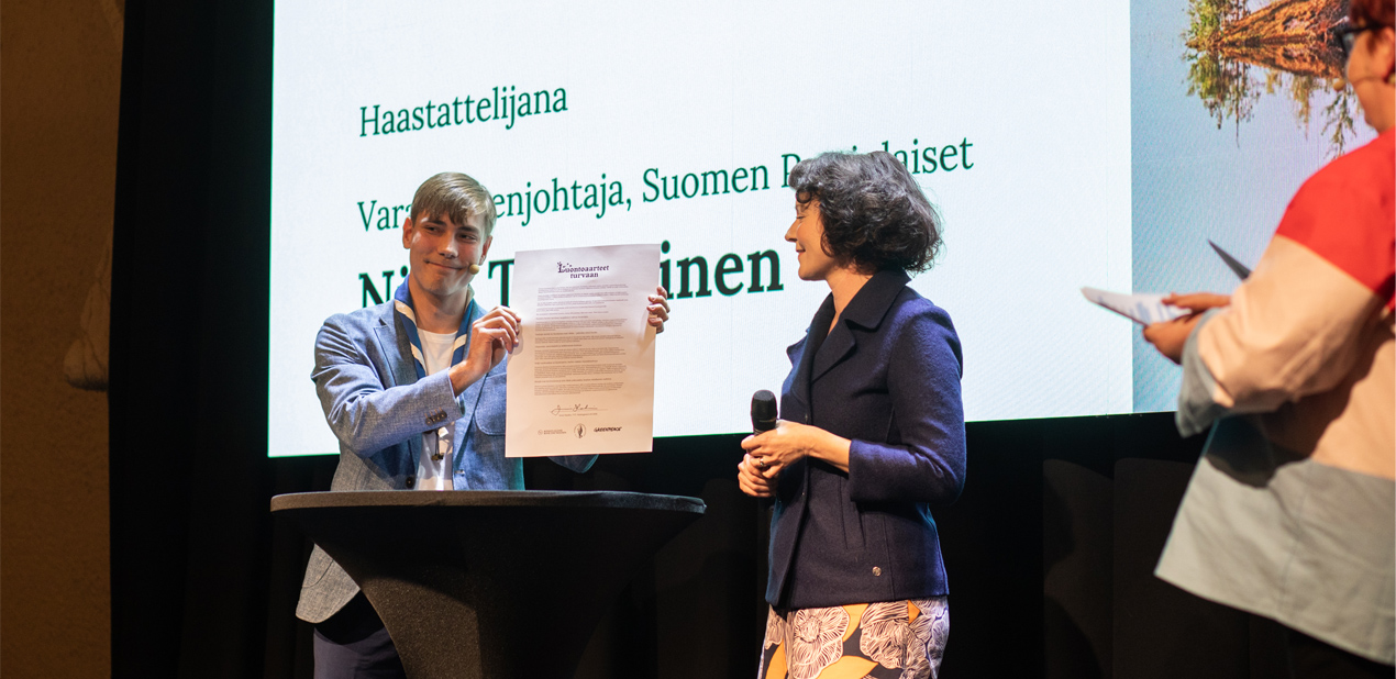 Jenni Haukio allekirjoittaa vetoomuksen Luontoaarteet turvaan -julkistustilaisuuden lavalla.